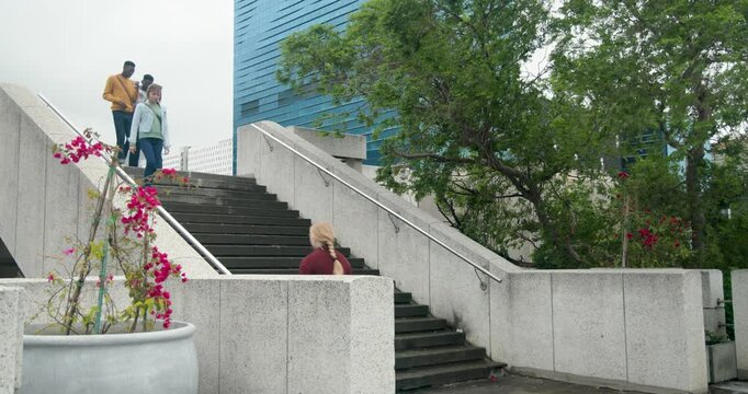 Diverse pedestrians descending stairs after arriving top, holding coffee cups and heading to camera