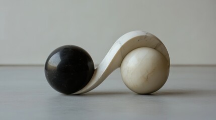 Smooth polished marble spheres in contrasting black and white held by a flowing cream colored sculpture