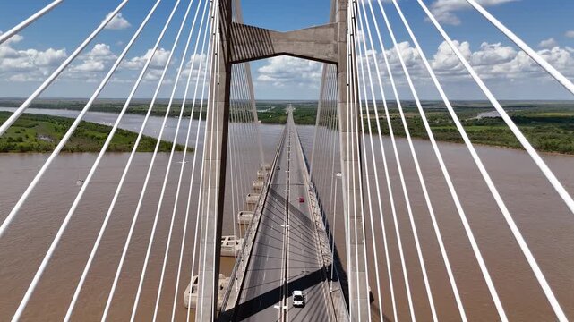 Aerial view pushing in toward Rosario-Victoria suspension bridge with highway and traffic in Argentina. Drone shot revealing road crossing over Parana River