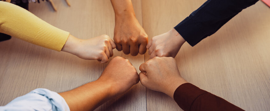 A vibrant scene depicting a diverse group of hands fist bumping in a collaborative office space, symbolizing teamwork, unity, and positive connections among colleagues. SACTR