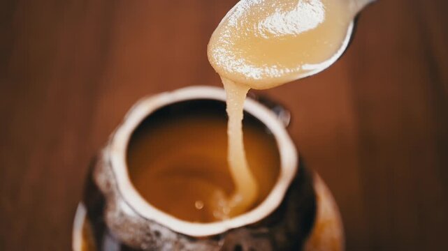 Slow-motion shot of thick honey dripping from a spoon, highlighting its viscosity and golden hue. Ideal for food and nature videos.