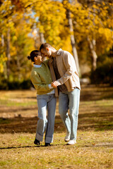 Fototapeta premium Couple enjoying a sunny autumn day while walking hand in hand in a park