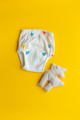 Reusable baby cotton diaper pantie on yellow background, top view. Eco friendly cloth