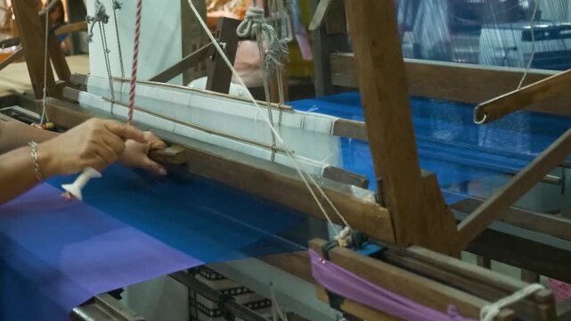 Artisan weaving silk threads on wooden handloom in traditional silk factory, Chiang Mai, Thailand. Handmade craftsmanship, artistry of textile production, sustainable vintage manufacture