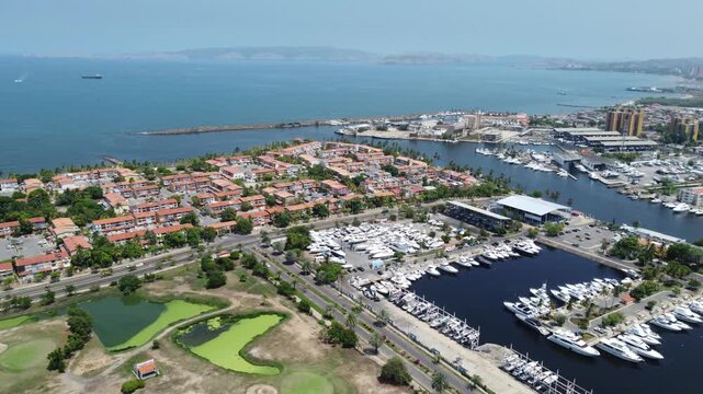 Cinematic aerial over Pueblo Viejo, Lecher&iacute;a, revealing luxury waterfront homes, navigable canals and boats under bright Caribbean skies.