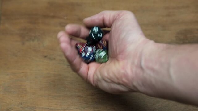 Shaking Polyhedral RPG Dice in Hand, close-up 4K shot of a hand holding and shaking various role-playing game dice before a throw. Concept of chance, anticipation, tabletop gaming, and hobby