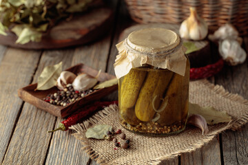 Homemade canned gherkins on a rustic wooden background.