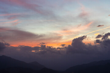 Bright sunset over the silhouette mountains at evening time.