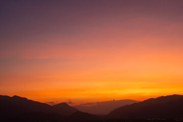 Bright sunset over the silhouette mountains at evening time.