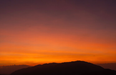 Bright sunset over the silhouette mountains at evening time.