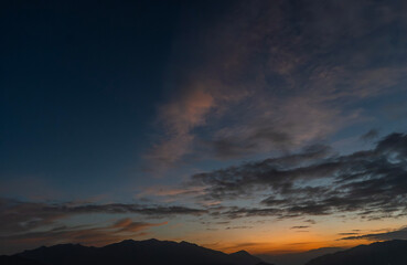 Bright sunset over the silhouette mountains at evening time.