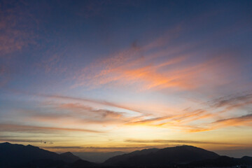 Bright sunset over the silhouette mountains at evening time.