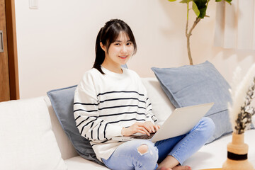 Fototapeta premium ソファでパソコンを使う女性