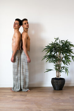 Stylish shirtless couple standing back-to-back indoors