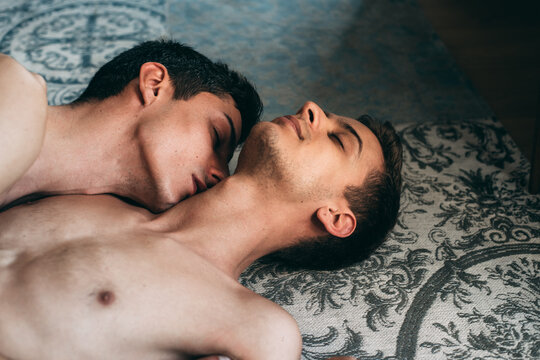 Intimate Gay Couple Resting Together on Patterned Surface Indoors