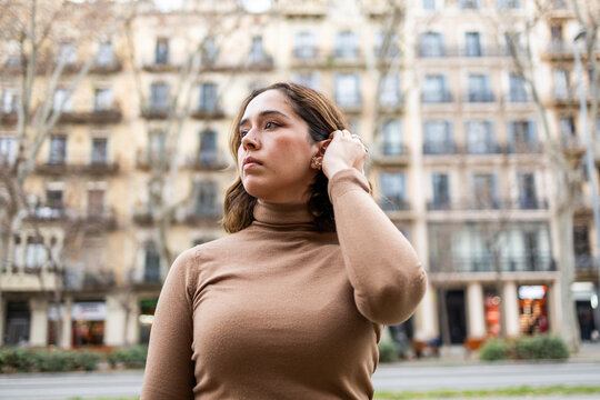 Woman in beige sweater outside urban building