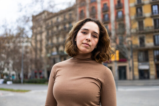 Woman in brown sweater standing in urban setting