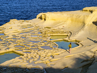 Impressive coastal landscape with salt pans and person at Zebbug on Gozo, Malta