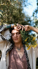 Beautiful brunette in boho style holds a bouquet of yellow flowers in her hands