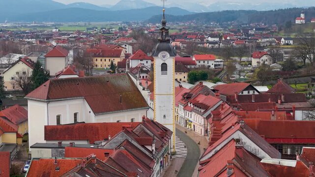 70mm Cinematic Pull-away from Kamnik Clock Tower and Chapel. Slow Drone Reveal of Central Street, Medieval Red Roofs and Snowy Alps. Alpine Aesthetics Slovenia Heritage 4K