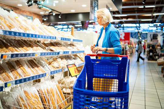 Mature woman shopping bread in grocery store bakery