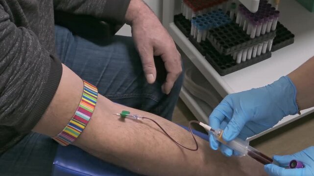 Medical blood collections procedure showing only nurses gloved hand and patient arm. Preventive heals check and blood donation concept.