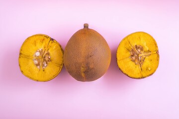 Fototapeta premium Fresh santol fruit cut in half on a pink background with whole fruit centered