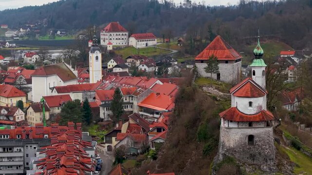 Panoramic View of Mali Grad Castle on Rock Cliff in Kamnik. Medieval Chapel with Triangular Roof and Central Church on Hilltop. Scenic Drone Footage of Slovenian Alps and Old Town Architecture 4K