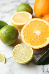 Different ripe citrus fruits on white marble table, closeup