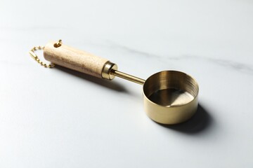 One golden scoop on white marble table, closeup