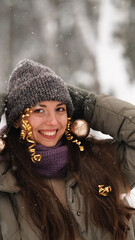 A beautiful young woman in winter clothes is happily spending her free time in a snowy forest. She enjoys the first snow. Active winter recreation.