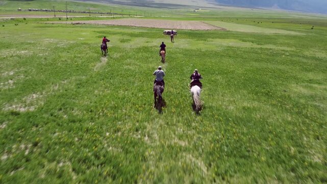 Men playing Kok Boru on horseback in rural Kyrgyzstan, low aerial drone view.