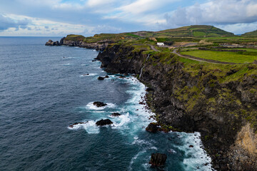 Rocky coastline with sea reefs cliffs on volcanic Sao Miguel Island, Azores. Atlantic Ocean shoreline of volcanic origin
