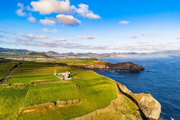 Lighthouse on Cape Cintrao surrounded by pastureland and steep cliffs, Sao Miguel, Azores