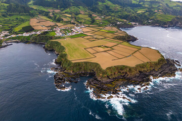 Terraced farmland with rugged basalt cliffs along Atlantic coastline of Sao Miguel, Azores, aerial view
