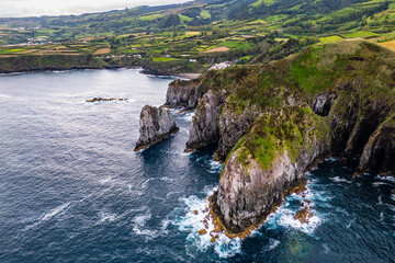 Coastal cliffs and strong Atlantic ocean hitting volcanic rock formations on Sao Miguel Island, aerial view