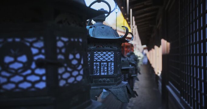 Line of beautiful, old lanterns hanging in shadows of ancient Japanese buildings - closeup
