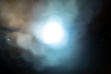 Soft blue and white flare with blurred bokeh circles on a dark abstract background, ideal for dreamy or futuristic design concepts and overlays. © kinomaster