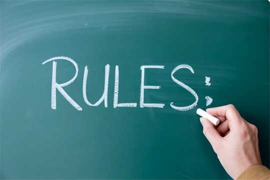 teacher hand write rule word on chalkboard. School and class rule
