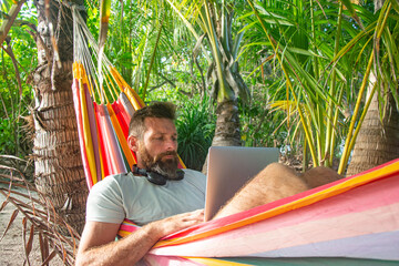 Digital Nomad Working on Laptop in Hammock on Tropical Beach