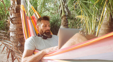 Digital Nomad Working on Laptop in Hammock on Tropical Beach