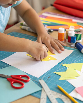 Child making paper craft with scissors at table