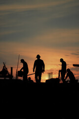 Fototapeta premium Silhouetted Workers Packing Painting Tools at Sunset in Cinematic Realism