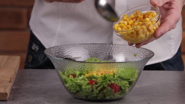 The cook adds cooked canned corn to the bowl and mixes the salad.