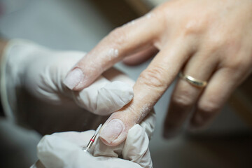 In a beauty salon, a manicurist is performing a machine-based dry manicure on a client's nails (Stock Photo).