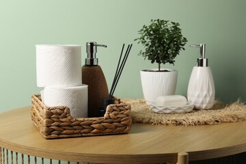 Toilet paper rolls, soap, aroma diffuser and houseplant on wooden table