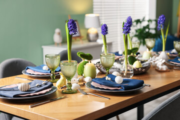 Easter celebration. Festive table setting with flowers and painted eggs indoors