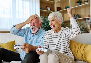 Portrait of senior couple having fun playing video games at home © Lumos sp