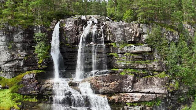 backward drone flight, reveal water and rocks of a big waterfall in Norway. Amazing nature, water falling from mountain, plants are growing on the rocks. Pure water, pristine nature. Tvindefossen. For