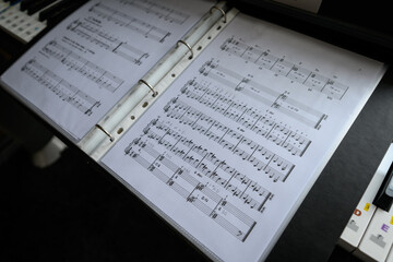 A view of sheet music in a folder lying on the piano keys.